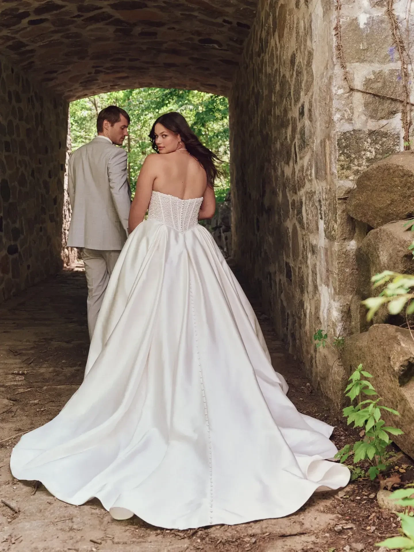 model is wearing a plus size strapless ball gown wedding dress
