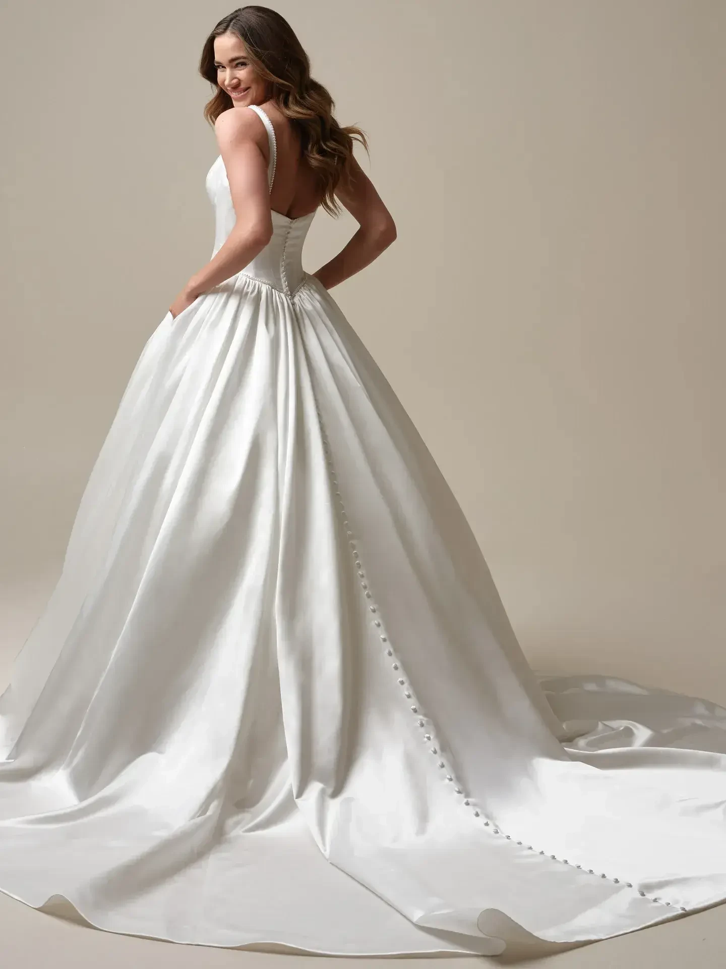 model is wearing a sleeveless ball gown with a square neckline