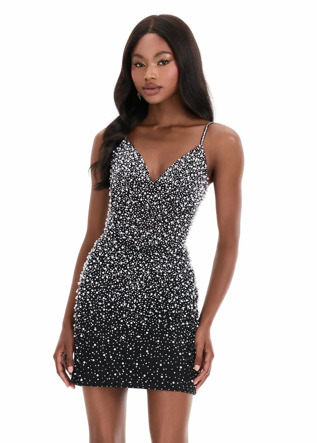 Model is wearing a fitted mini dress with thin straps, a lace overlay, sparkling embellishments, and a V-neckline.