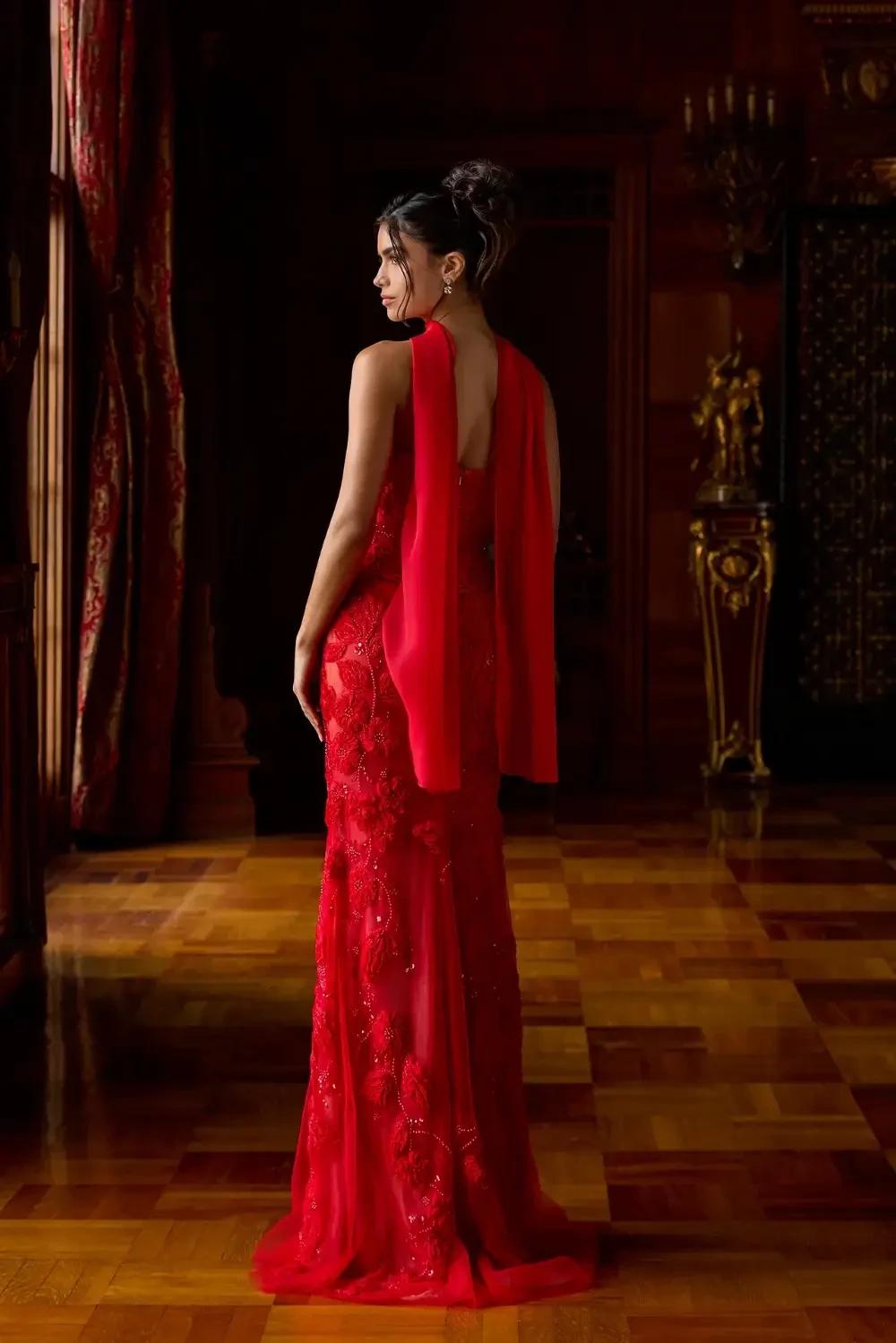 model is wearing a bold red evening gown with a neck scarf