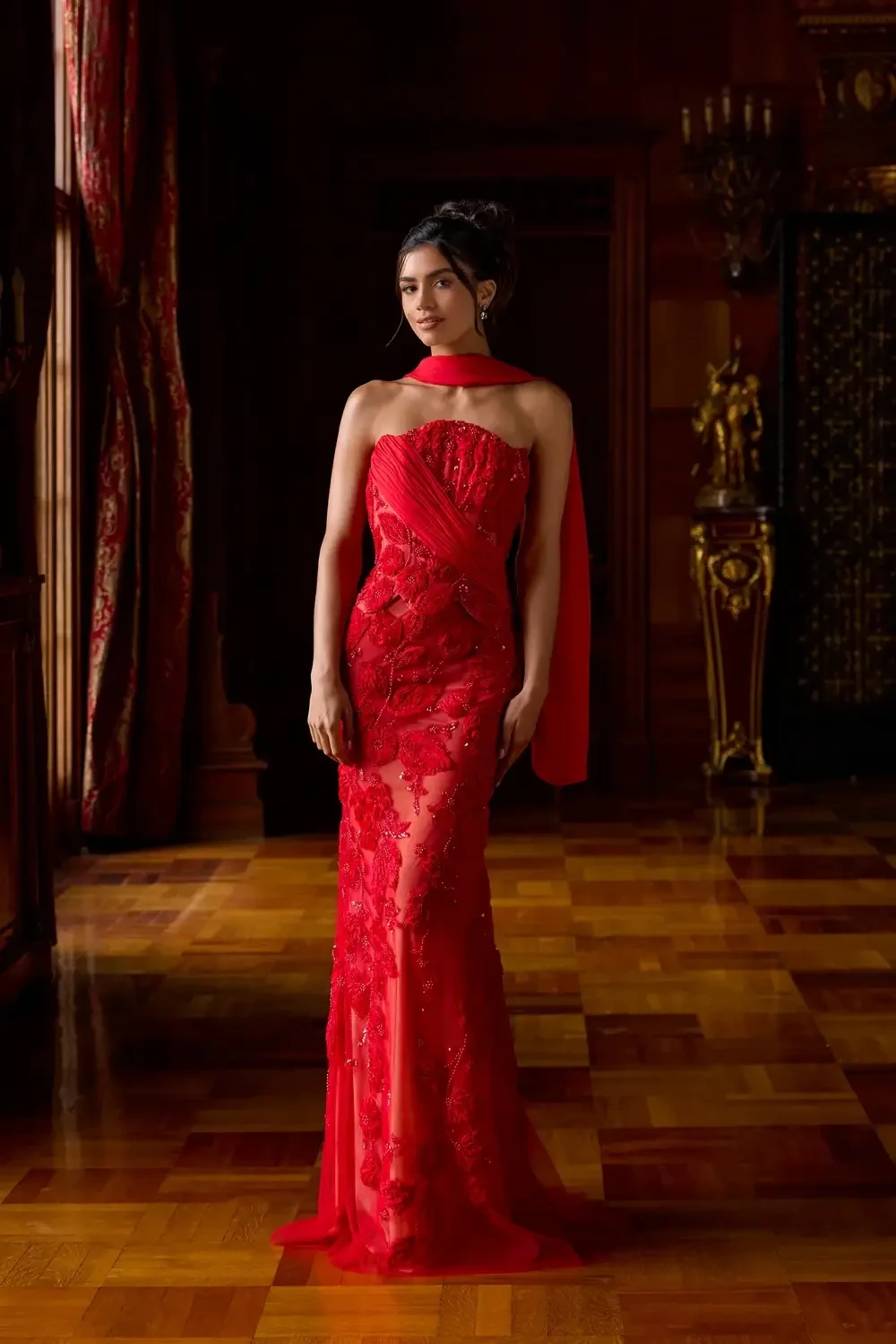 model is wearing a bold red evening gown with a neck scarf
